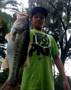 Happy young angler with large bass caught on guided bass trip in winter haven just south of Orlando Florida